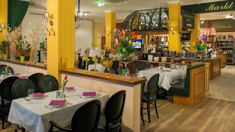 restaurant_d3s9354-copy_media, © Kaiserrast Restaurant with tables separated by half walls and yellow concrete columns. The kitchen is discreetly visible in the background.