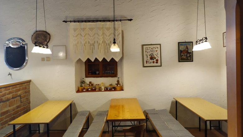 Cozy parlor, © Weinbau Maier Cozy parlor with wooden tables and benches, decorated with pictures and lamps.