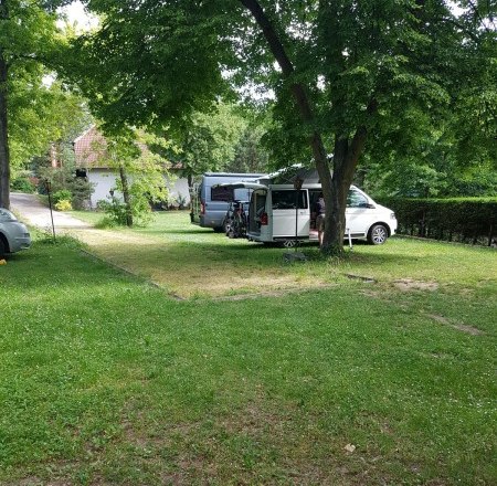 Campsite, © Waldcamping Hubertus Two mobile homes are parked under trees on a green campsite.