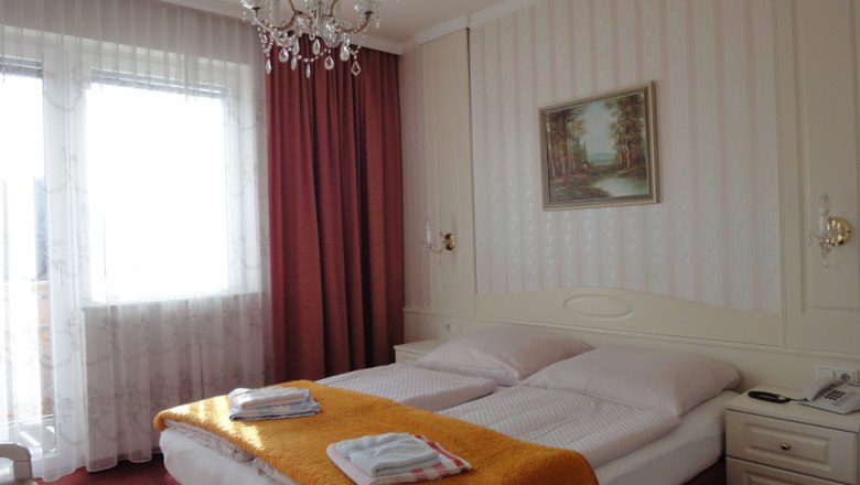 Room 12, © Rosner Elisabeth Hotel room with double bed, chandelier and painting on the wall.