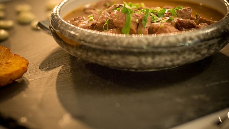 Restaurant - Lamb stew, © Schlossschenke A chocolate volcano dessert on a slate plate decorated with a scoop of ice cream and red rose petals.
