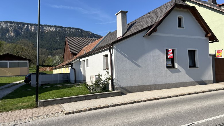 Summer cottage, © Anton Sommer A white house with a red roof and a "For Rent" sign in front of a mountain backdrop.