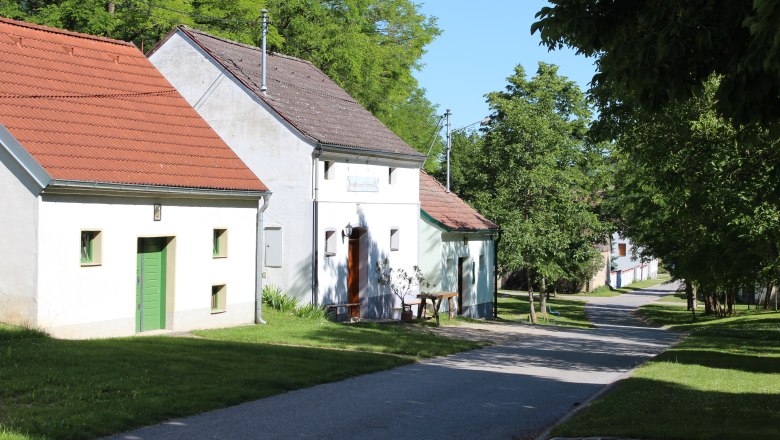 Wine cellar lane Fuchsenweg, © Weinviertel Tourismus A quiet street with traditional houses and green trees on a sunny day.