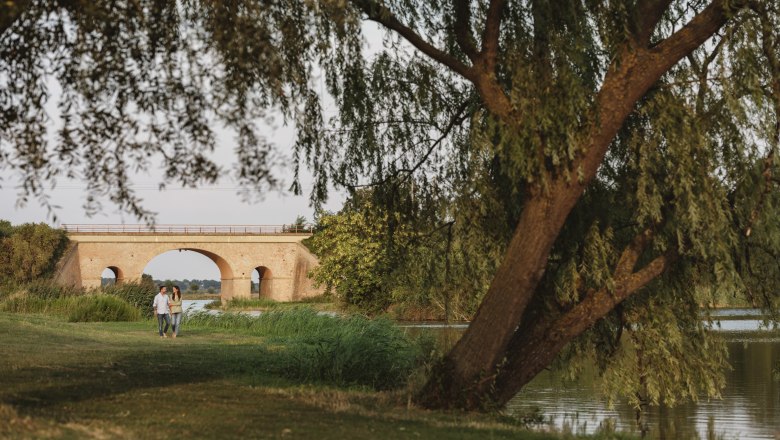 Landscape pond in Bernhardsthal, © Michael Reidinger Couple walking by a pond with a bridge in the background.