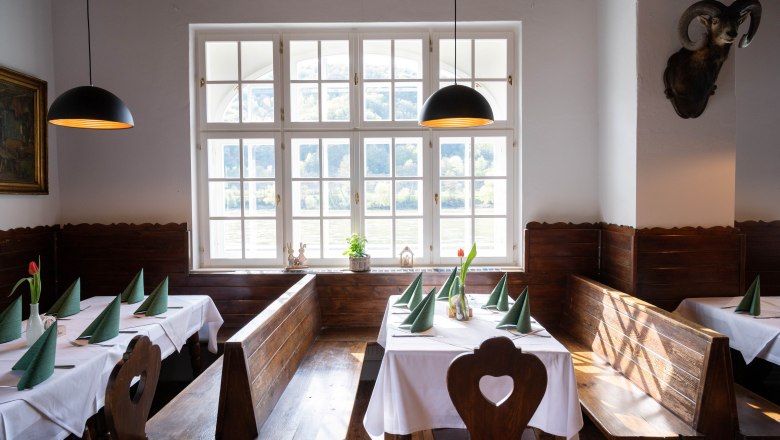 Restaurant in the Aggsteinerhof, © Daniels Cozy dining room with wooden benches, white tablecloths and green napkins. Large windows with a view of nature.