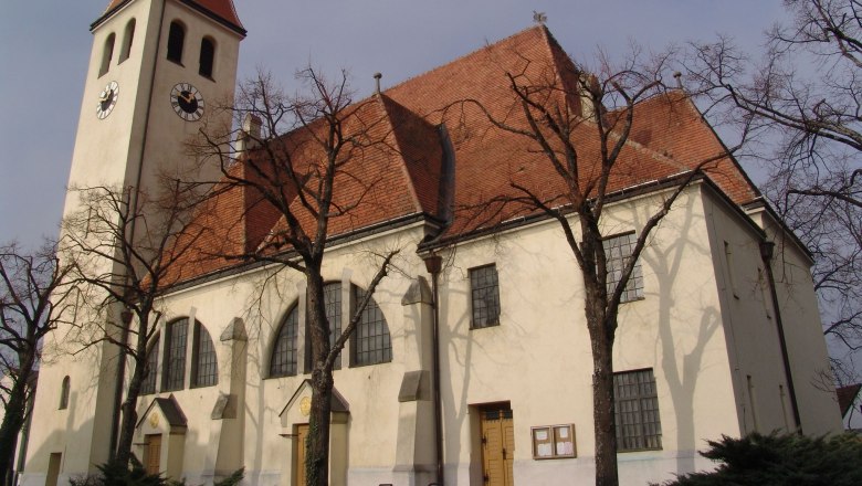Church in Enzersfeld, © Pfarre Enzersfeld Church with tower and red tiled roof, surrounded by bare trees.