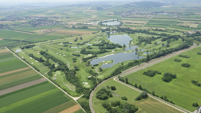 Flyover, © DCC Aerial view of a golf course with lakes and surrounding fields.