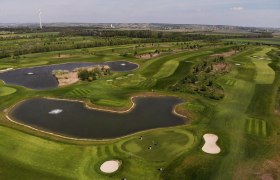 GolfRange in Bockfließ, © Golfclub Bockfliess Aerial view of a golf course with ponds and wind turbine in the background.