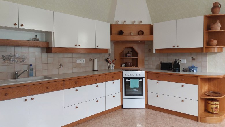 Eat-in kitchen, © Erika Kellner Kitchen with white and wood-colored cabinets, stove and sink.