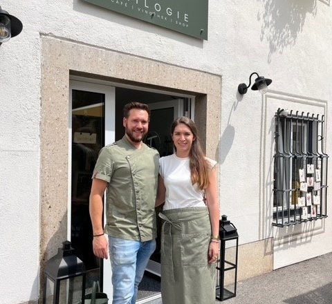 Bernhard & Elisabeth, © Elisabeth Pammer A man and a woman are standing outside a café called Trilogie.