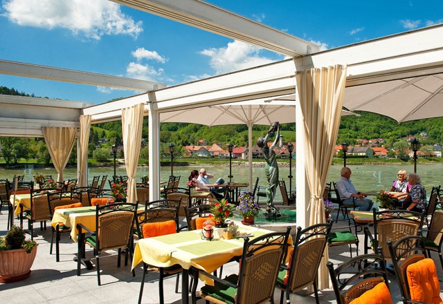 Restaurant terrace, © Residenz Wachau Restaurant terrace with a view of a river and green hills in the background.