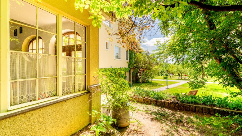 Woltron Manor, © Wiener Alpen / Christian Kremsl A manor house with large windows and a well-tended garden in the sunshine.