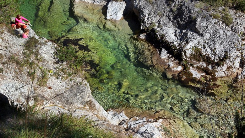 Hiking in the Ötschergräben, © weinfranz.at Two people are sitting on a rock next to a clear, green river in a gorge.
