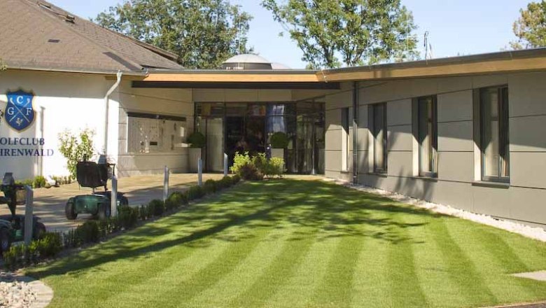 Clubhouse Golfclub Föhrenwald, © Golfclub Föhrenwald Entrance to the clubhouse of the Föhrenwald Golf Club with manicured lawn and modern buildings.