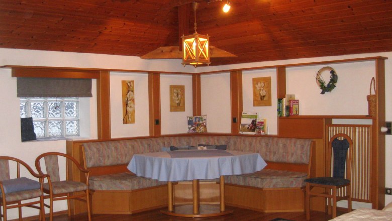 Room 2, © Kienesberger Cozy sitting area with wooden furniture and blue tablecloth in a room with a wooden ceiling.