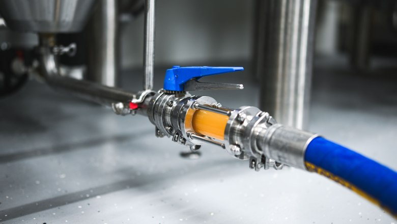 brewstable_brewday, © Hofbrauerei Braustall_Georg Schwameis Close-up of a brewery hose with valve and liquid flowing through it.