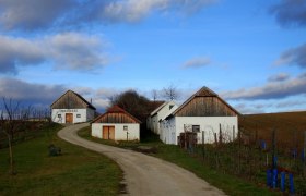 Hundsbergkellergasse Hart-Aschendorf, © Marktgemeinde Wullersdorf Wine cellar in a rural landscape with blue sky and clouds.