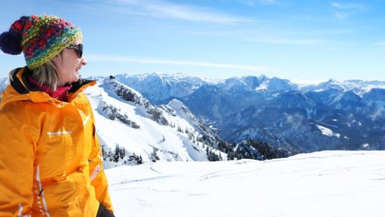 JoSchi's ski school, © weinfranz.at Woman in a colorful cap and yellow jacket looks at snow-covered mountains.