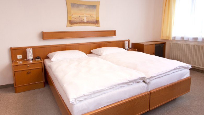 Room view, © Gasthof zur Sonne A hotel room with a double bed, wooden furniture and a picture on the wall.