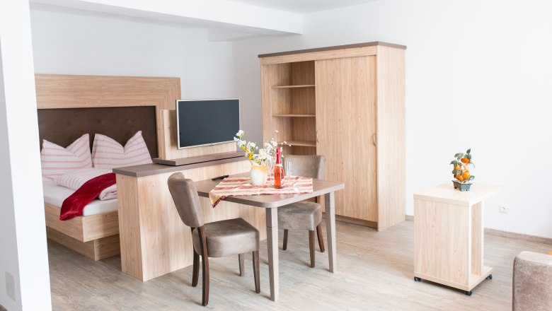 Apartment house Bergsee, © Familie Daurer Modern apartment with wooden furniture, bed, table and TV.