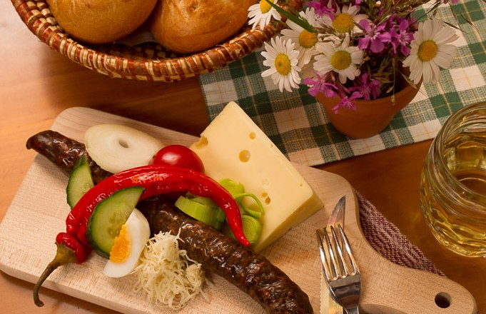 Snack, © © Langthaler A traditional snack board with sausage, cheese, vegetables and bread on a wooden table.