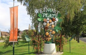 Largest grape in Lower Austria, © Dorferneuerungsverein Platt Welcome sign in Platt with grape decoration and church in the background.