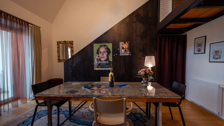 At the Park Hotel, © Niederösterreich Werbung / Maximilian Pawlikowsky A stylishly furnished room with a table, chairs, a lamp and posters on the wall.