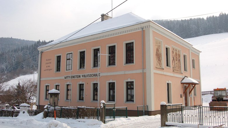 Wittgenstein School Trattenbach, © Wolfgang Glock A two-storey, pink school building in the snow with the inscription 'Wittgenstein Volksschule'.