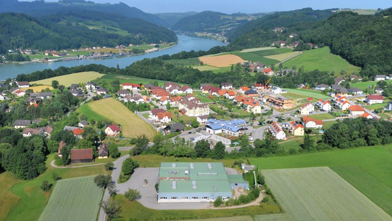 View of the Danube valley, © Gemeinde Hofamt Priel Aerial view of a village in the Danube valley with river and hills in the background.