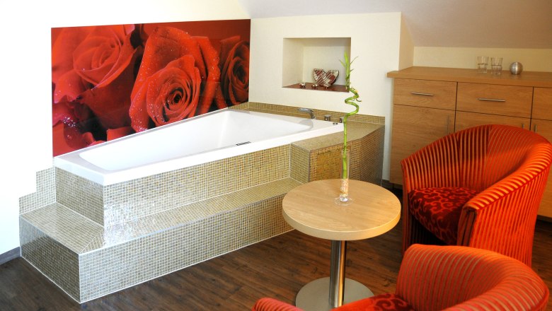 Premium bon-vivant rooms at Schreiners - the Waldviertel House, © Schreiners – das Waldviertel Haus Cozy room with bathtub, red armchairs and a picture of roses on the wall.