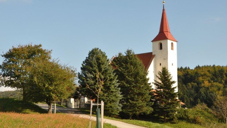 Ofenbach parish church, © Thermengemeinden Ofenbach parish church with red tower roof, surrounded by trees and meadows.