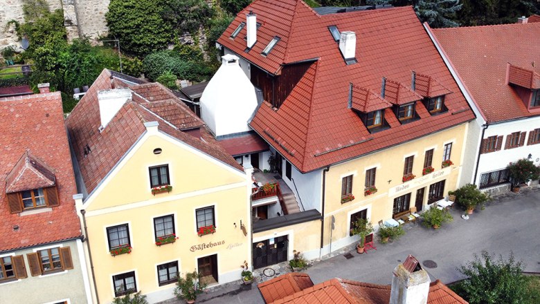 Pension Guesthouse Heller, © Annemarie Heller Aerial view of a yellow guest house with red roofs and flower boxes.