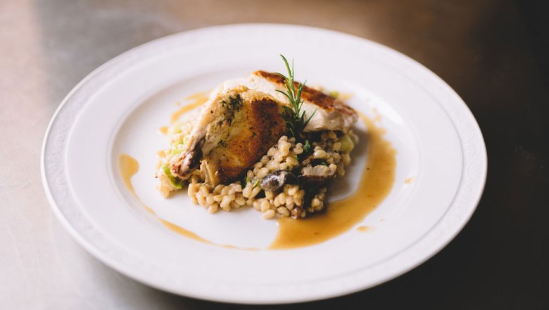 Corn chicken with porcini mushroom and tender wheat risotto, © Niederösterreich Werbung/Mara Hohla A plate of corn-fed chicken and porcini mushroom and tender wheat risotto, garnished with rosemary.