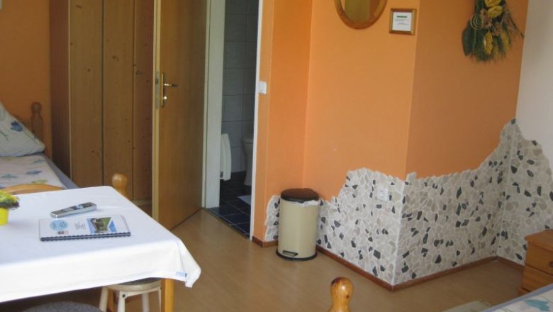 Room, © Zelenka A cozy room with wooden furniture, a table, chairs and an open bathroom.