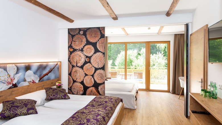 Family room, © Martina Siebenhandl A modern family room with wooden floor, two beds, large windows and decorative wooden elements.