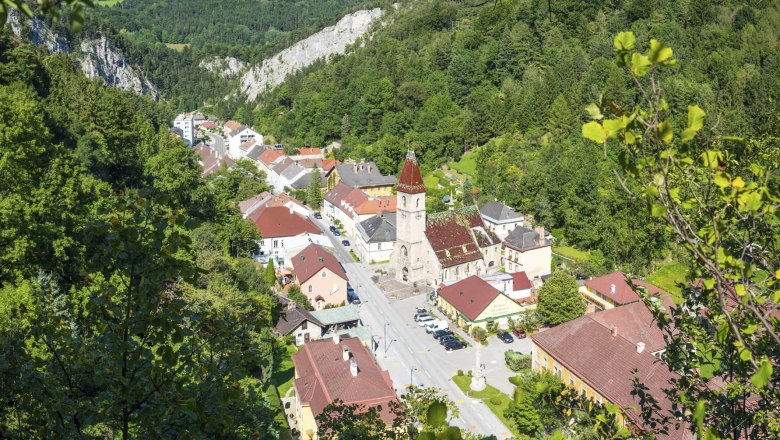 Schottwien, © Marktgemeinde Schottwien/Zwickl Aerial view of Schottwien with church and surrounding buildings, surrounded by wooded hills.