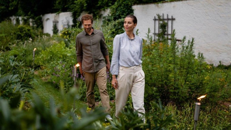 Historic courtyard garden Seitenstetten Abbey, © Unrath A man and a woman walk through a green garden surrounded by plants.