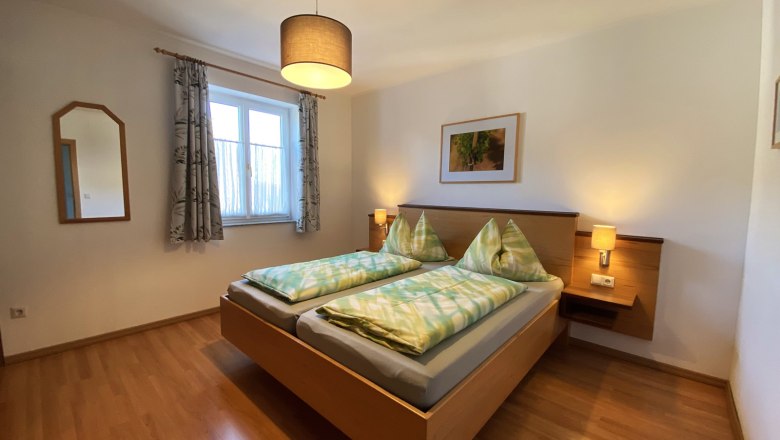 Vacation apartment Traube, © Trachsler Bedroom with double bed, wooden floor, bedside tables and lamp.