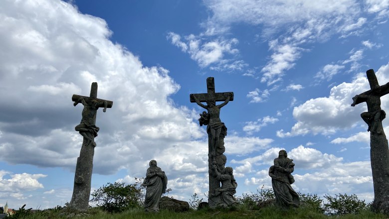 Calvary vineyard, © Weinstraße Weinviertel Three stone crosses with figures on a hill under a cloudy sky.