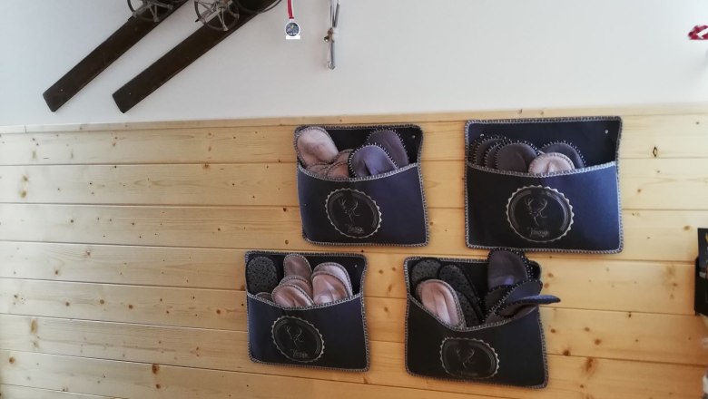 Entrance, © Familie Weibels Entrance area with wooden paneling, old skis on the wall and felt slippers in pockets.