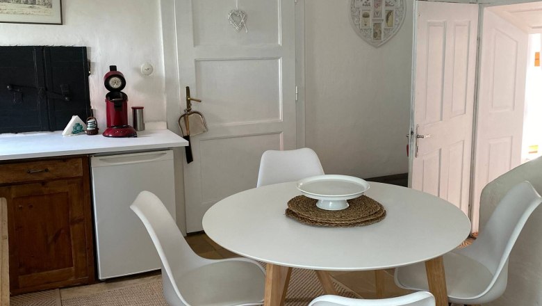 Sitting area in the kitchen, © Familie Stagard Kitchen seating area with round table and four white chairs on a carpet.