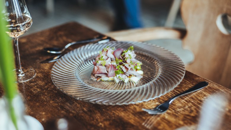 Roast beef and asparagus salad, © Niederösterreich Werbung/David Schreiber A plate of roast beef and asparagus salad on a wooden table, with a glass of white wine next to it.