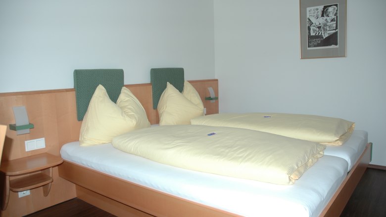 Hotel Zur Alten Schule, © Viregro Capital Gmbh Hotel room with double bed, yellow bed linen and mural.