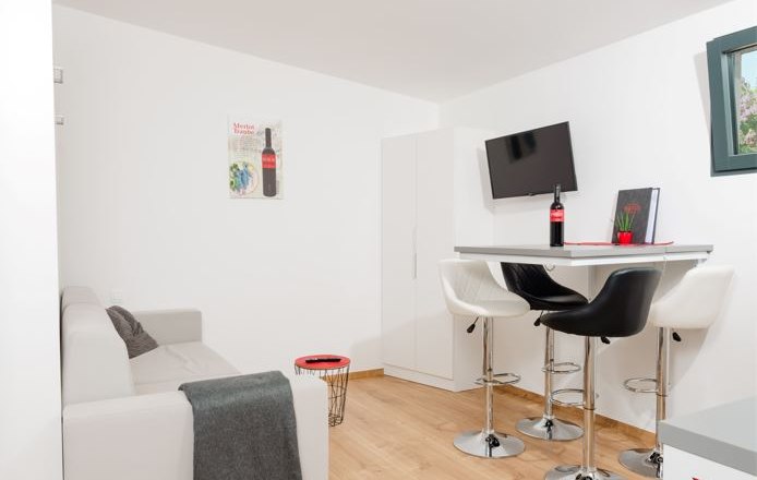 Ipsmiller Apartments, © Michael Reidinger Modern living room with sofa, dining table and bar stools.