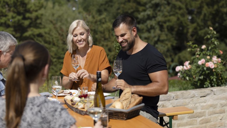 Winter wine tavern, © Weinviertel Tourismus GmbH / Schwarz-König Group of people sitting at an outdoor table enjoying wine and bread.