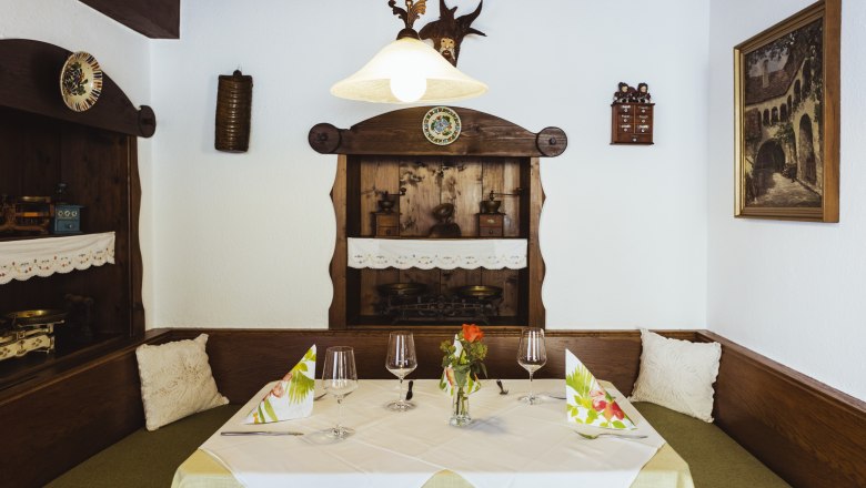 Guest room with loving details, © Niederösterreich Werbung/David Schreiber Cozy seating area in a restaurant with wooden furniture, decorative details and table setting.