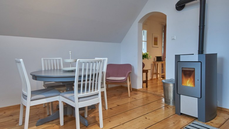 Top 2 - Living room, © VP FeWo OG Cozy living room with dining table, chairs, armchair and fireplace.