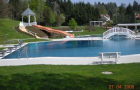 Eichgraben adventure pool, © Gemeinde Eichgraben Outdoor pool with slide, bridge and pavilion in the background.
