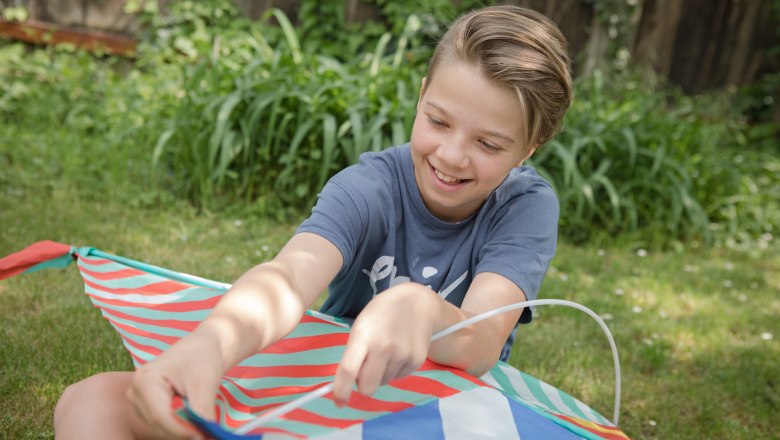 Child in meadow, © Weinviertel Tourismus GmbH / Lahofer A child sits in the grass and holds a colorful kite in his hands.