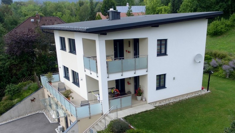 Drone image of Haus Weinengel, © Familie Harrauer Drone shot of a modern two-story house with balcony and garden.